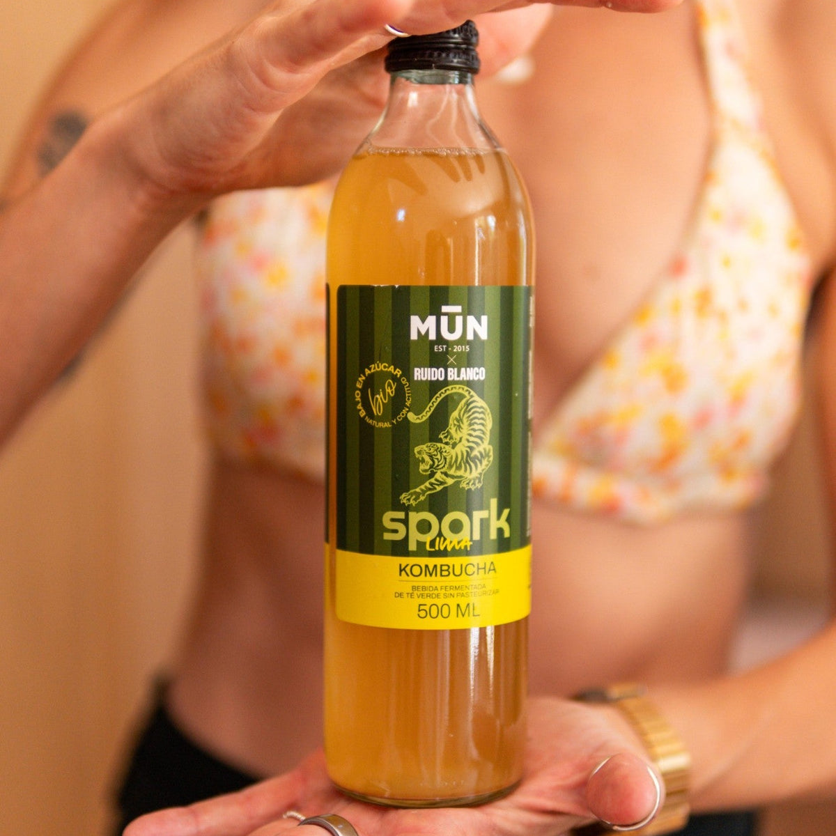 Botella de kombucha Mūn x Ruido Blanco SPARK lima de 500 ml sostenida entre las manos